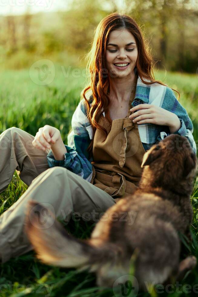 femme sur le herbe avec sa chien dans le parc dans le soir avec ensoleillement souriant photo