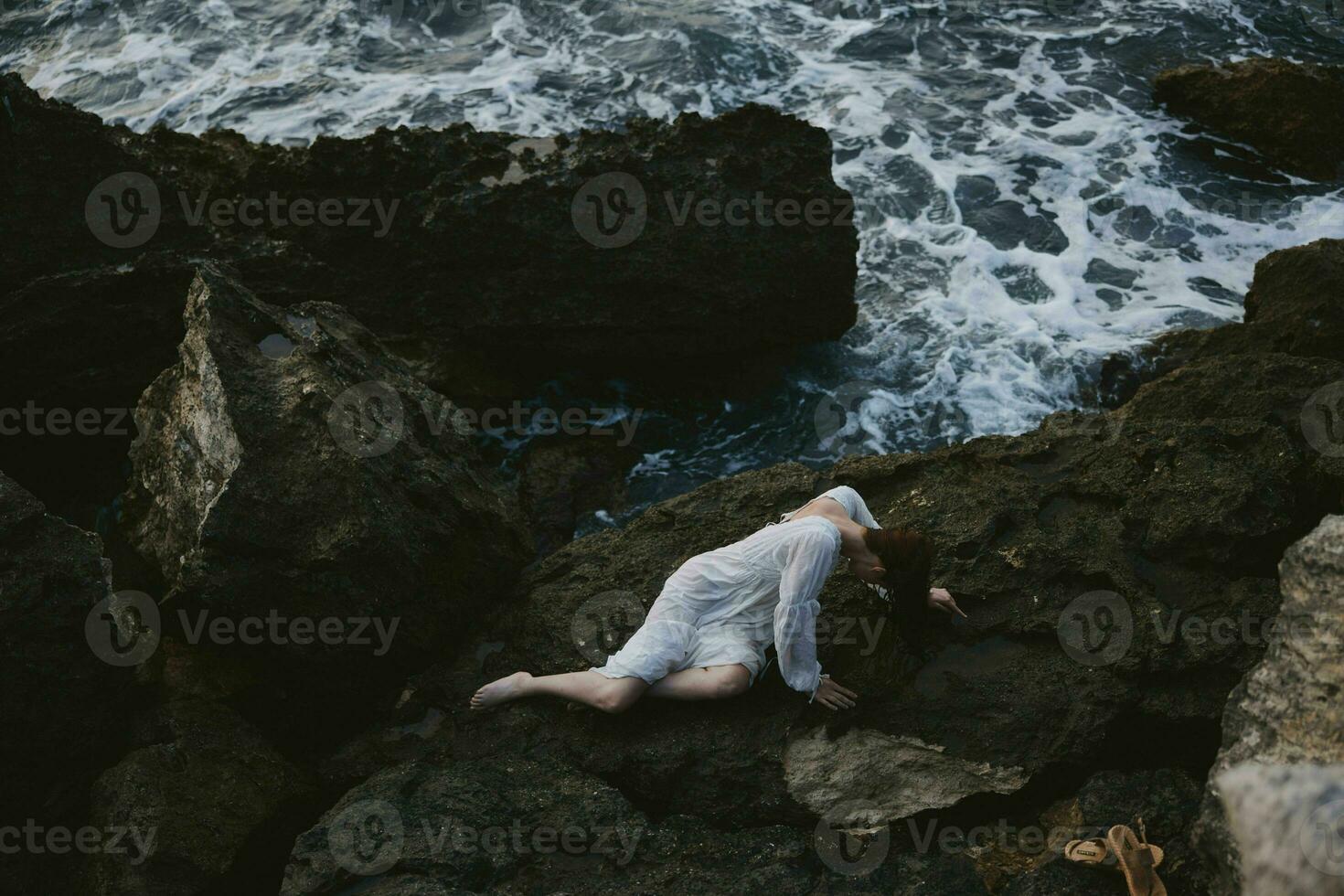 pieds nus femme dans une blanc robe mensonge sur une pierre dans une blanc robe paysage photo