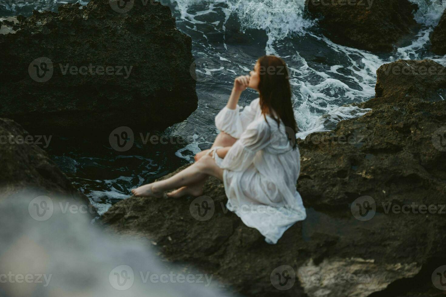 femme dans blanc mariage robe pieds nus séance sur une pierre la nature photo