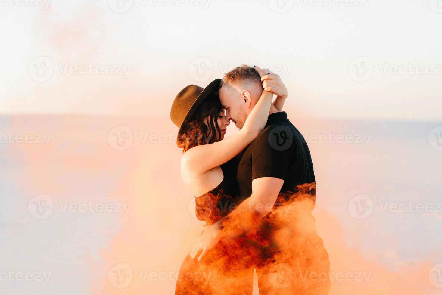 mec et une fille en vêtements noirs étreignent et courent sur le sable blanc photo