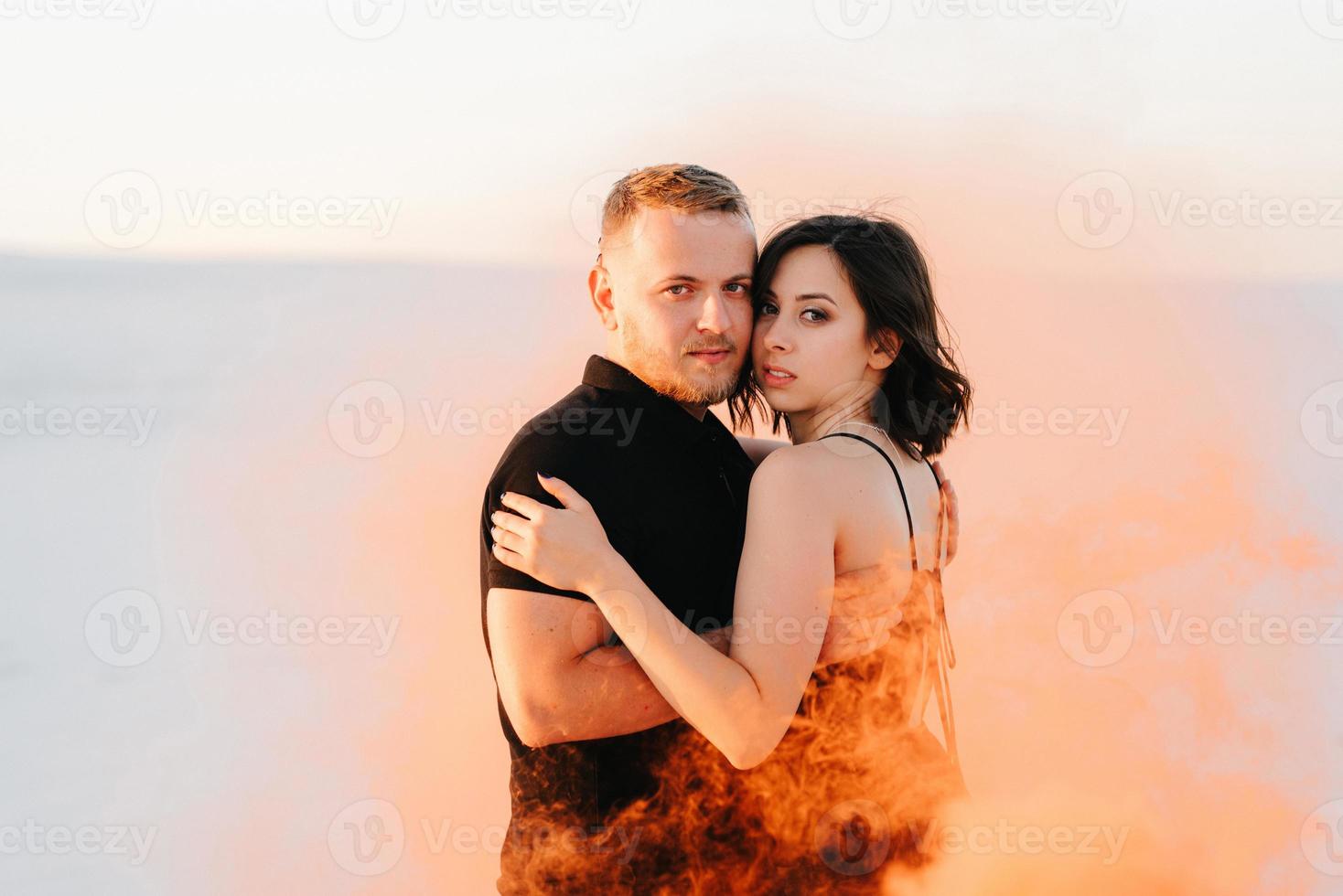 mec et une fille en vêtements noirs étreignent et courent sur le sable blanc photo