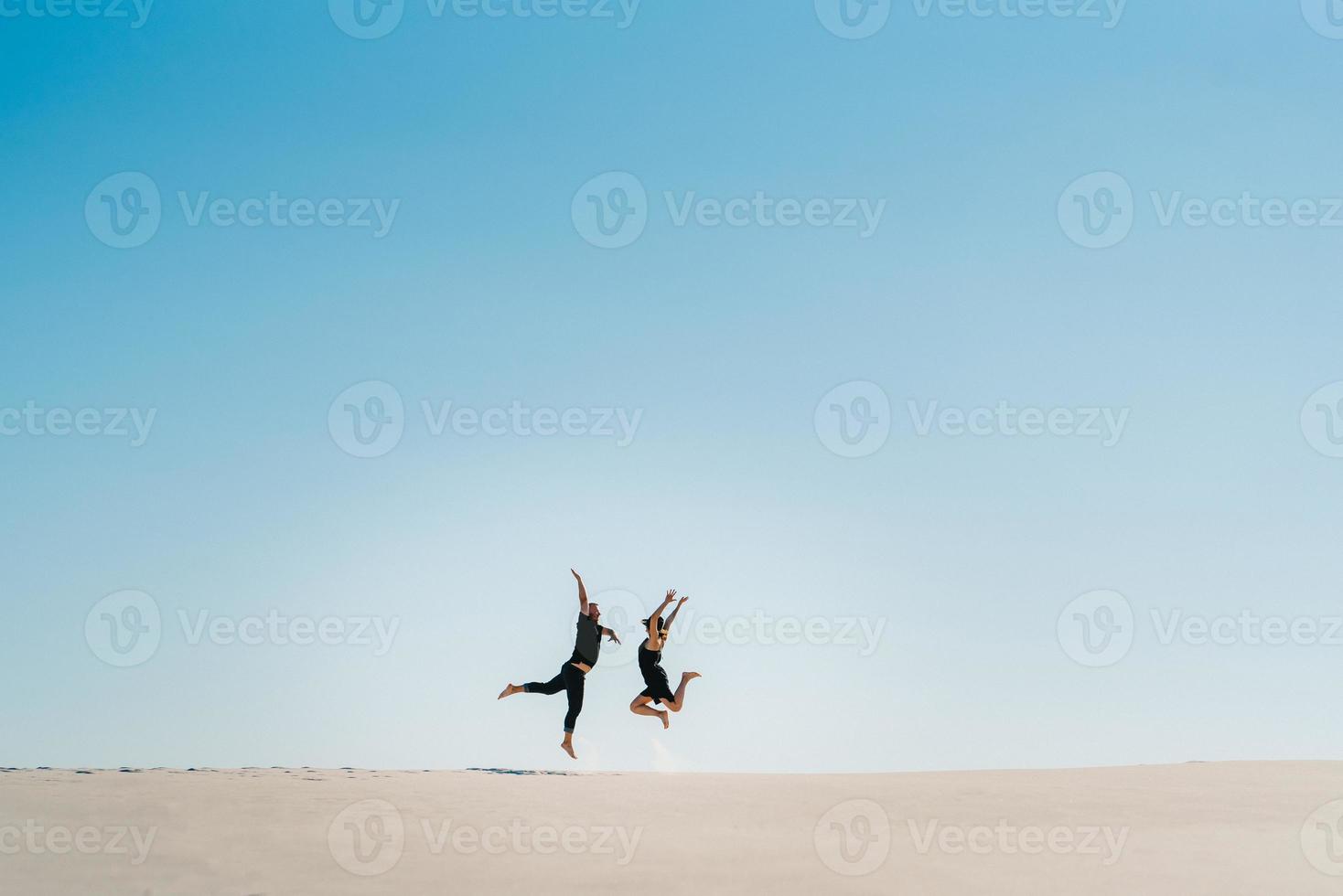 jeune couple, un mec et une fille avec des émotions joyeuses dans des vêtements noirs marchent à travers le désert blanc photo