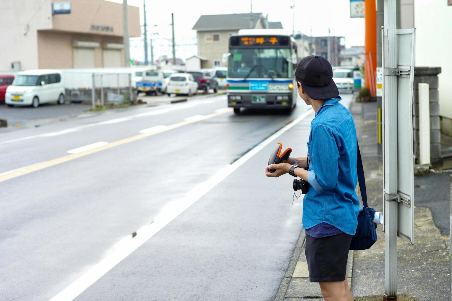 retour portrait de touriste masculin non identifié en attente de bus à l'arrêt. photo