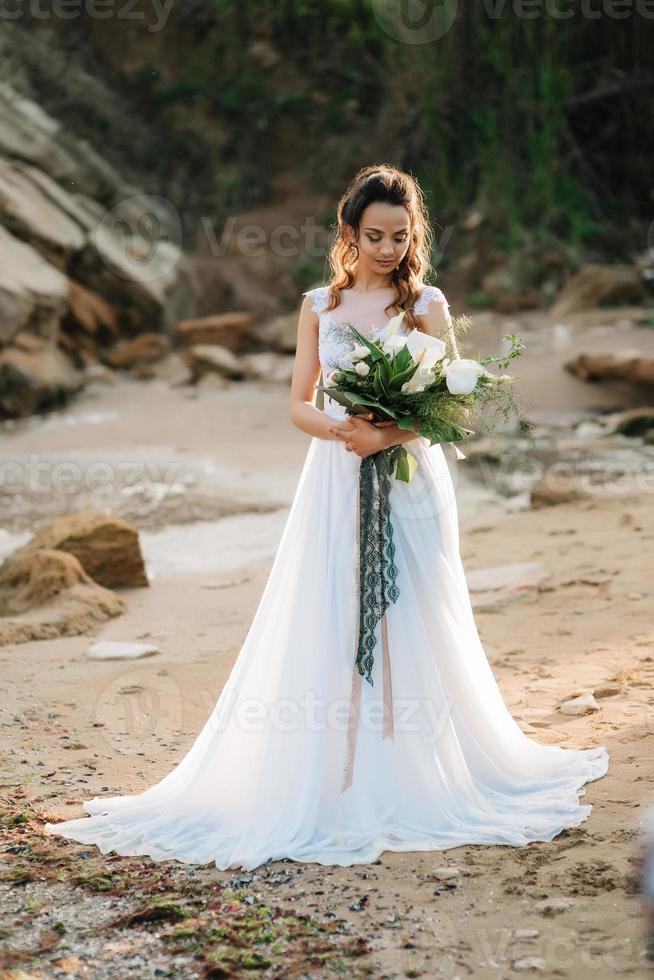 mariée avec un bouquet de mariage au bord de la mer photo