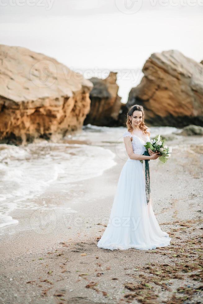 mariée avec un bouquet de mariage au bord de la mer photo