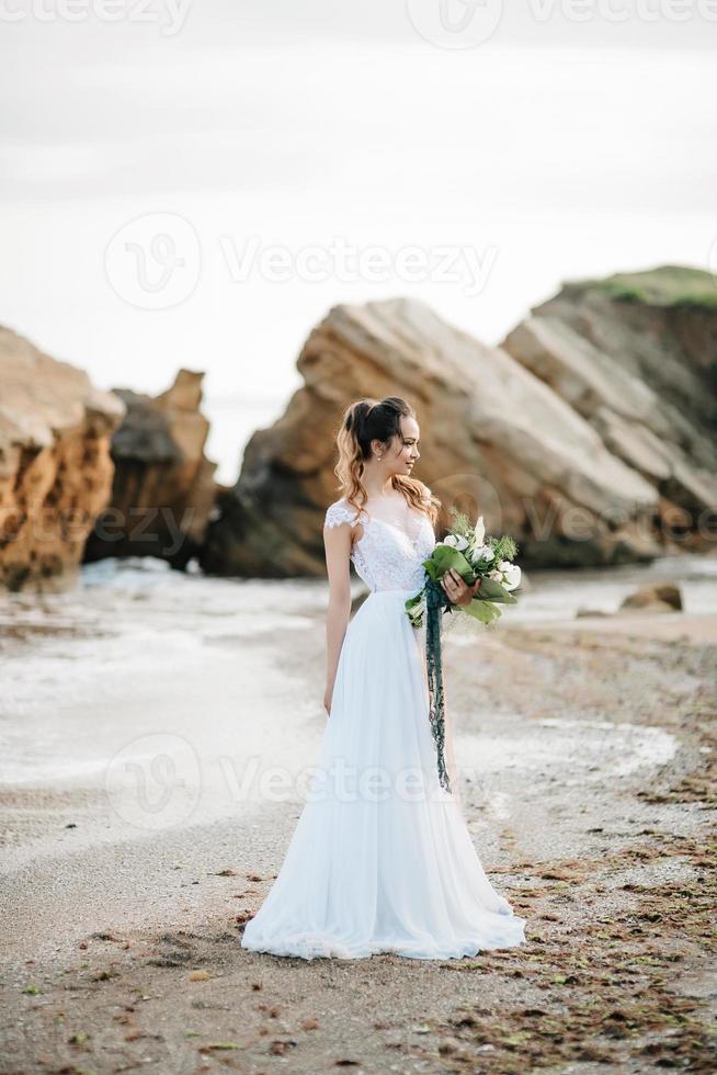 mariée avec un bouquet de mariage au bord de la mer photo