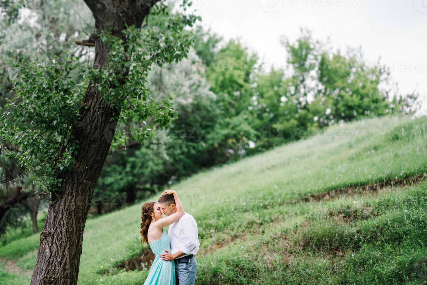 mec heureux dans une chemise blanche et une fille dans une robe turquoise se promènent dans le parc forestier photo