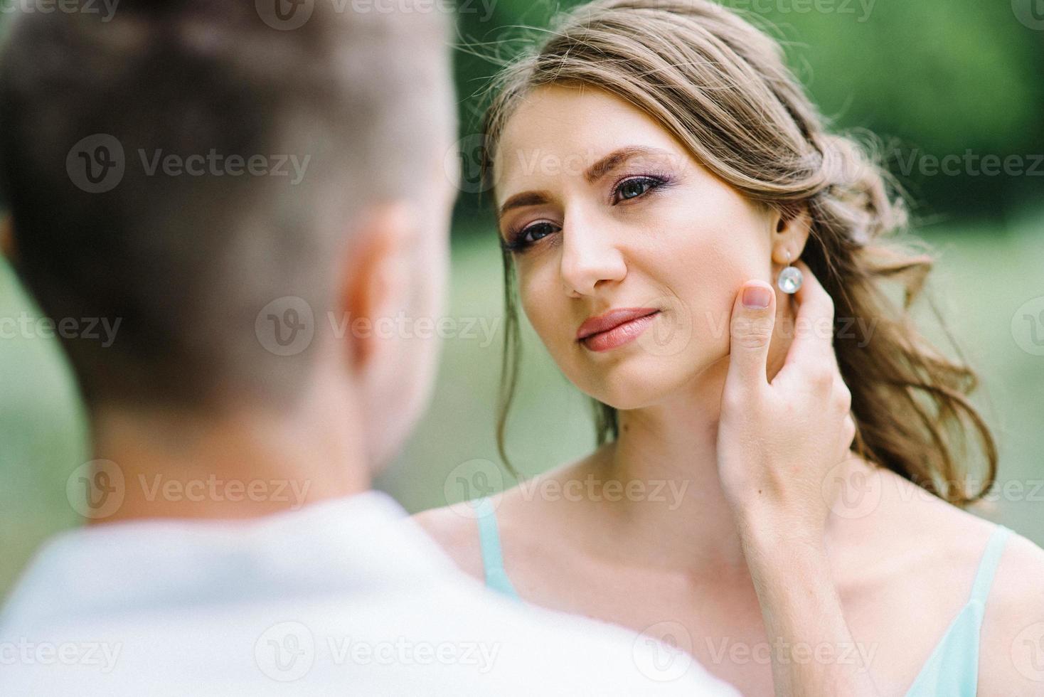 mec heureux dans une chemise blanche et une fille dans une robe turquoise se promènent dans le parc forestier photo