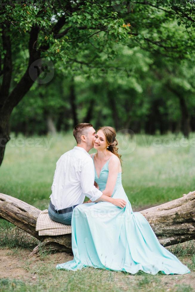 mec heureux dans une chemise blanche et une fille dans une robe turquoise se promènent dans le parc forestier photo