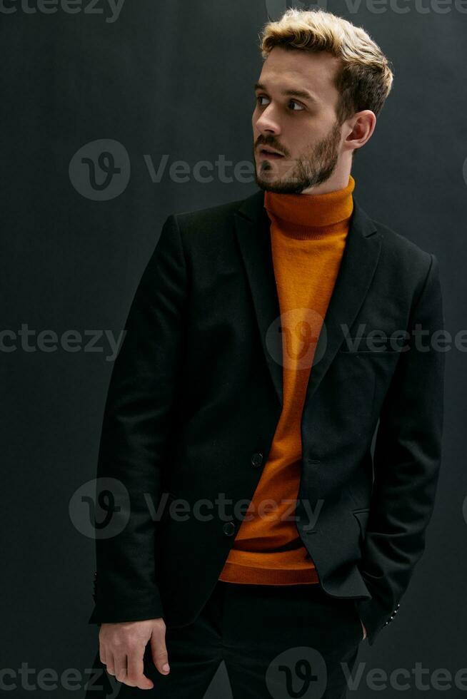 élégant homme dans classique costume Orange chandail manteau noir Contexte tendance de le saison photo