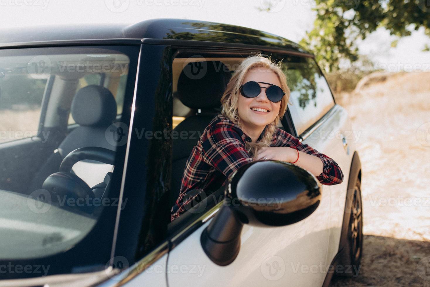 Fille blonde avec des nattes dans une chemise jeans chaussures rouges et lunettes noires photo