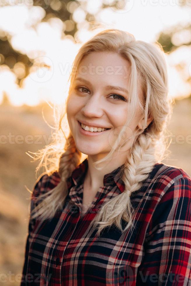 Blonde avec des nattes dans une chemise jeans chaussures rouges souriant photo