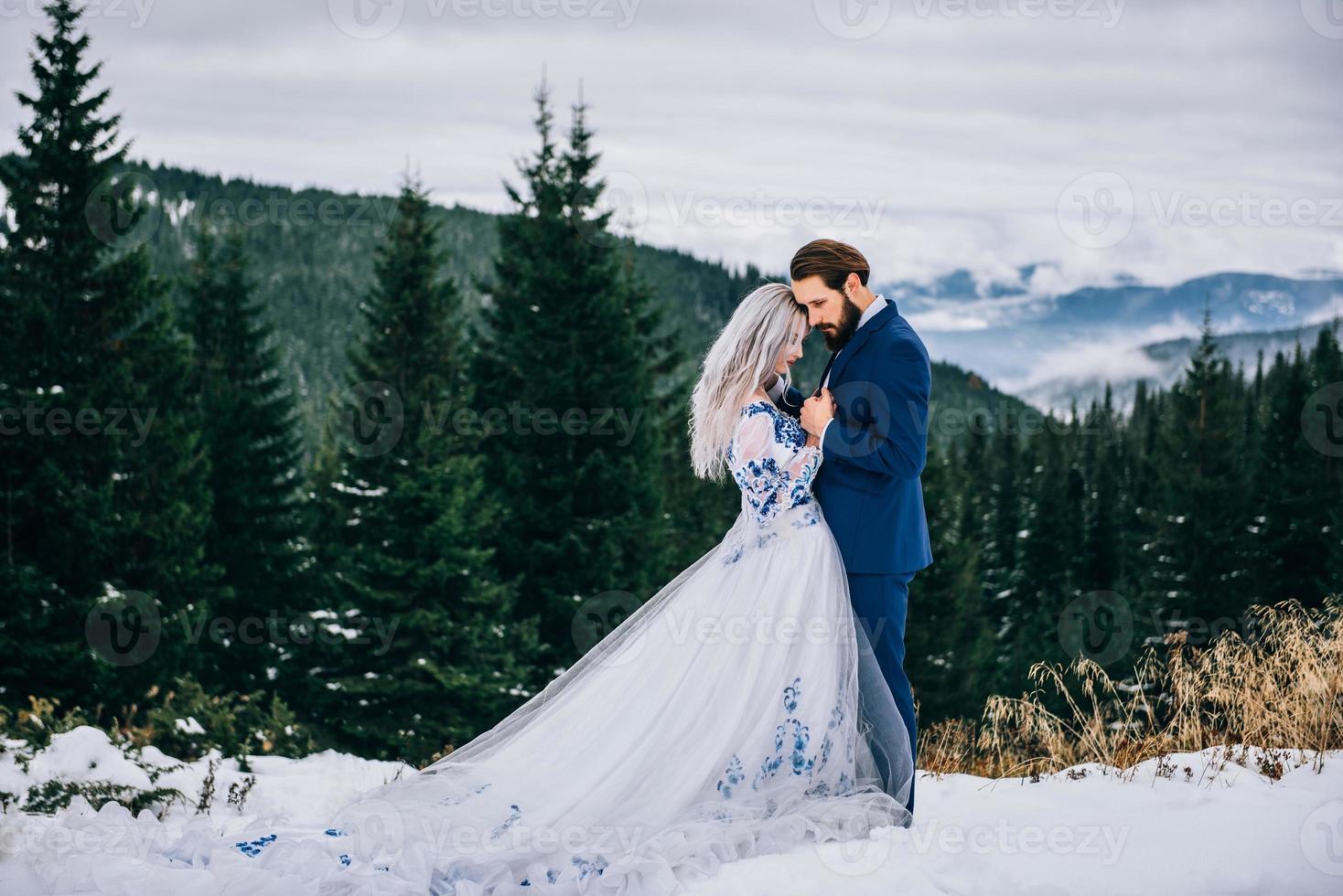 Marié dans un costume bleu et mariée en blanc dans les montagnes des Carpates photo