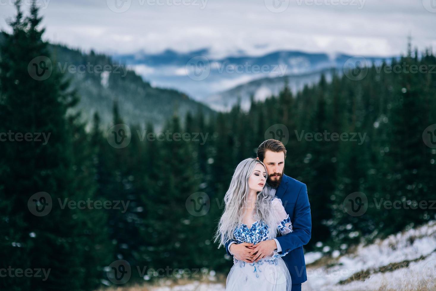 Marié dans un costume bleu et mariée en blanc dans les montagnes des Carpates photo