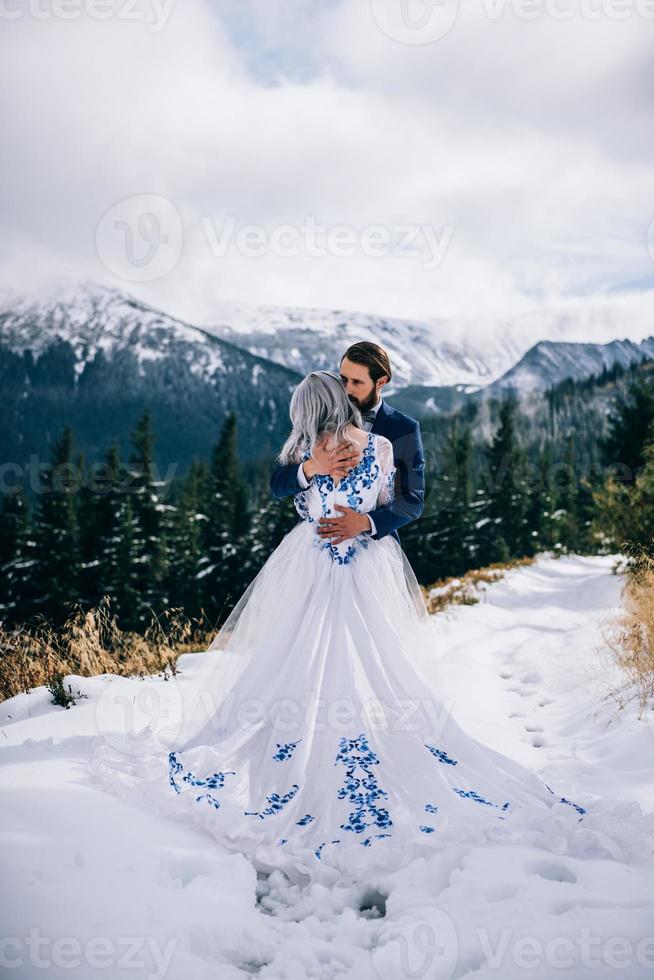 Marié dans un costume bleu et mariée en blanc dans les montagnes des Carpates photo