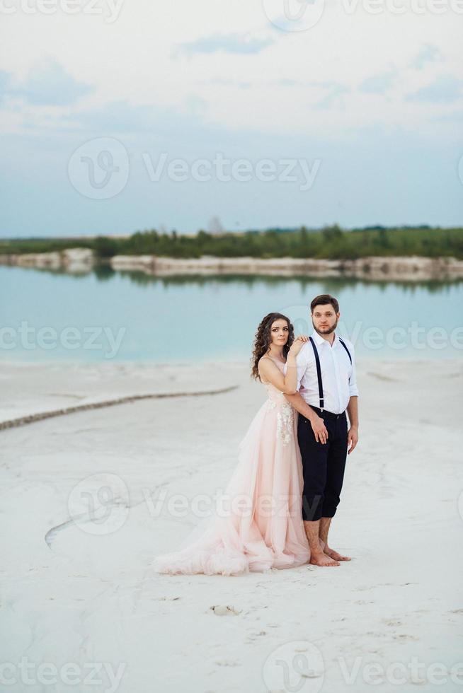 jeune couple un mec en culotte noire et une fille en robe rose marchent le long du sable blanc photo