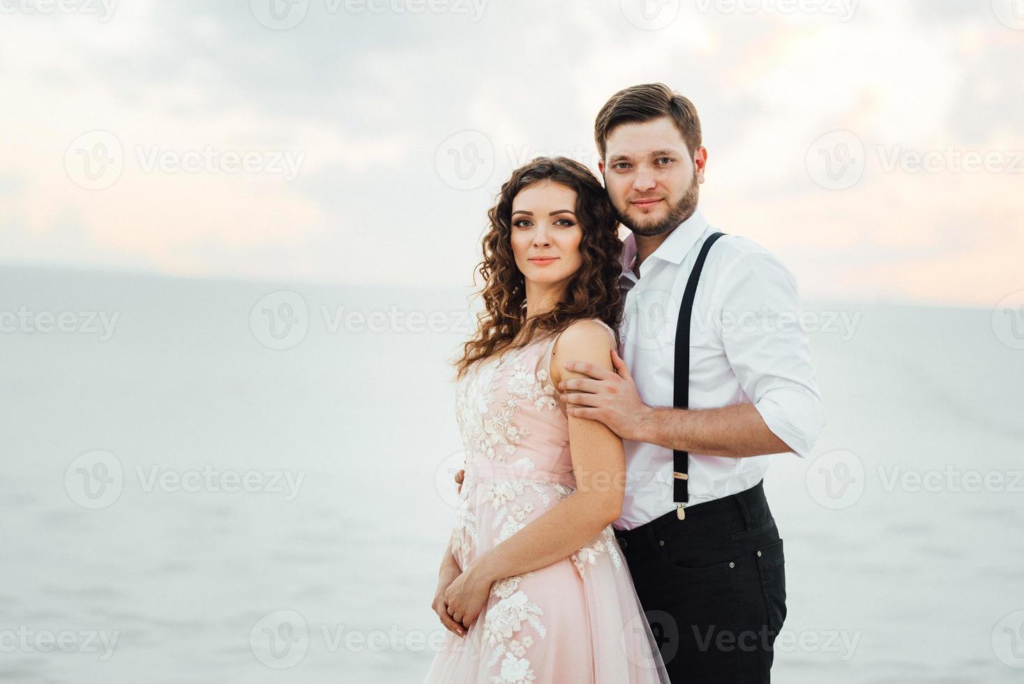 jeune couple un mec en culotte noire et une fille en robe rose marchent le long du sable blanc photo