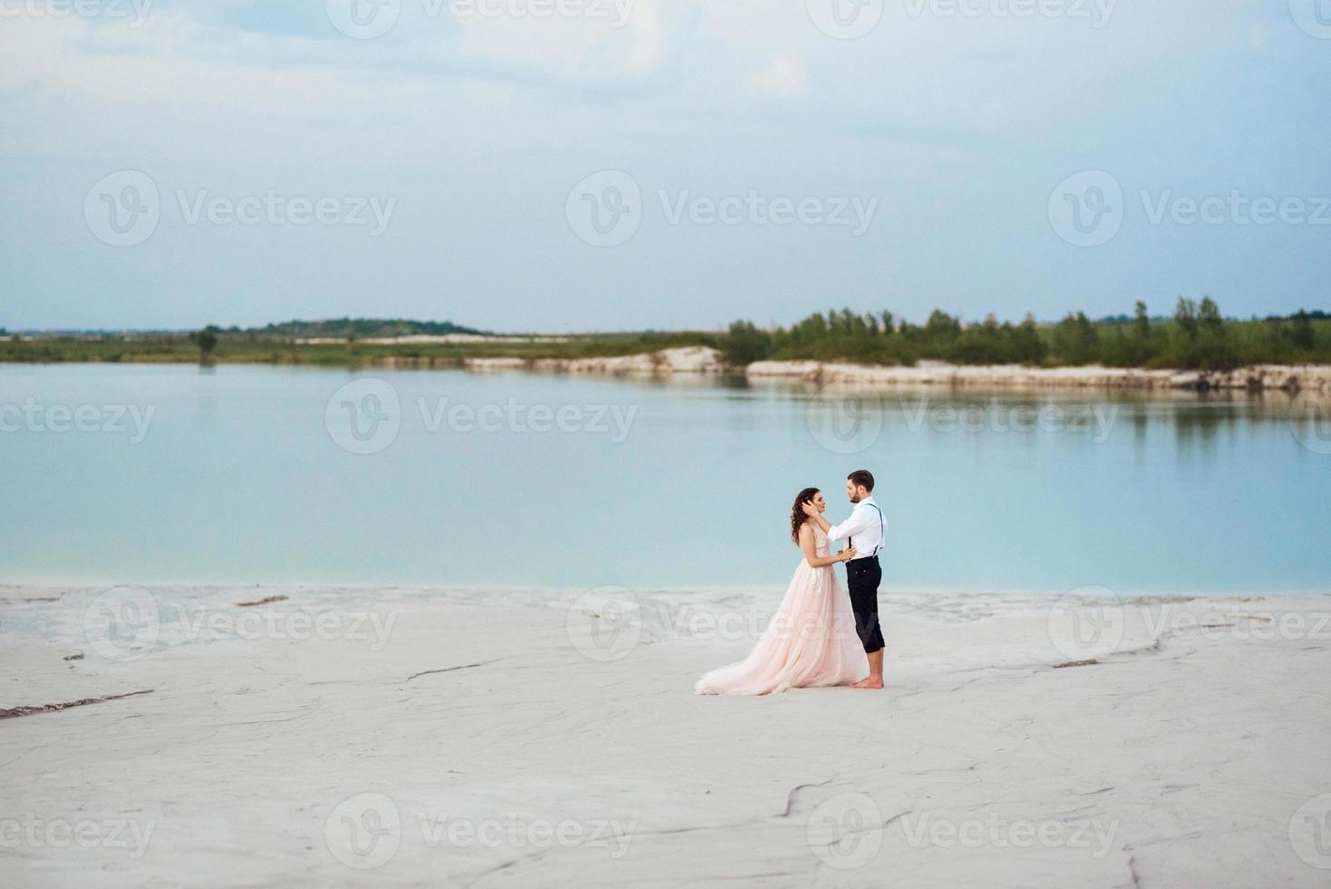 jeune couple un mec en culotte noire et une fille en robe rose marchent le long du sable blanc photo