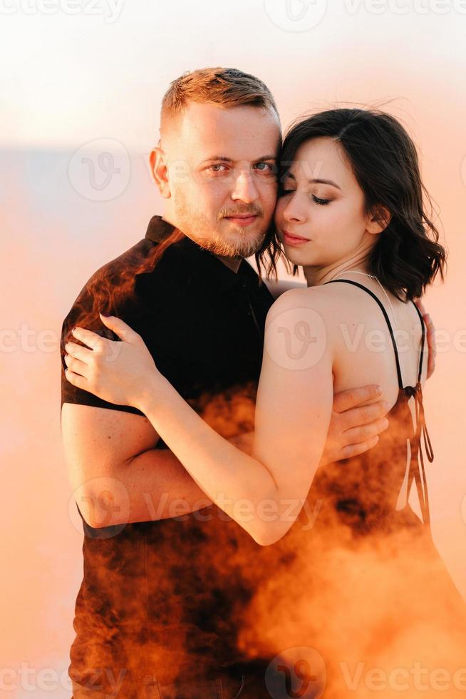 mec et une fille en vêtements noirs étreignent et courent sur le sable blanc photo