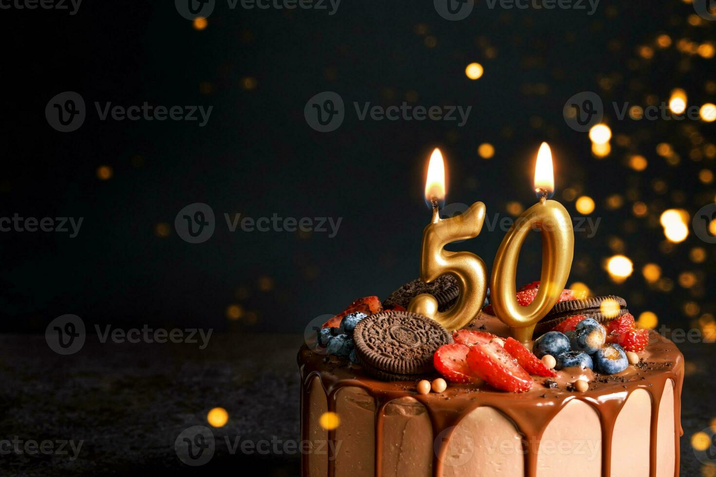 Chocolat anniversaire gâteau avec baies, biscuits et nombre cinquante d'or bougies sur noir arrière-plan, copie espace photo