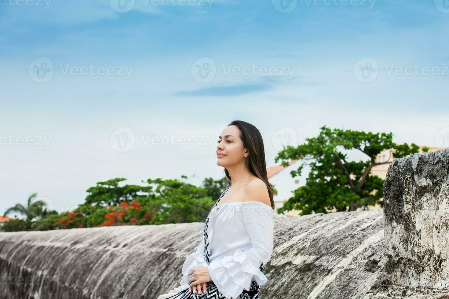 magnifique femme sur blanc robe séance seul à le des murs alentours le colonial ville de Carthagène de Indes photo