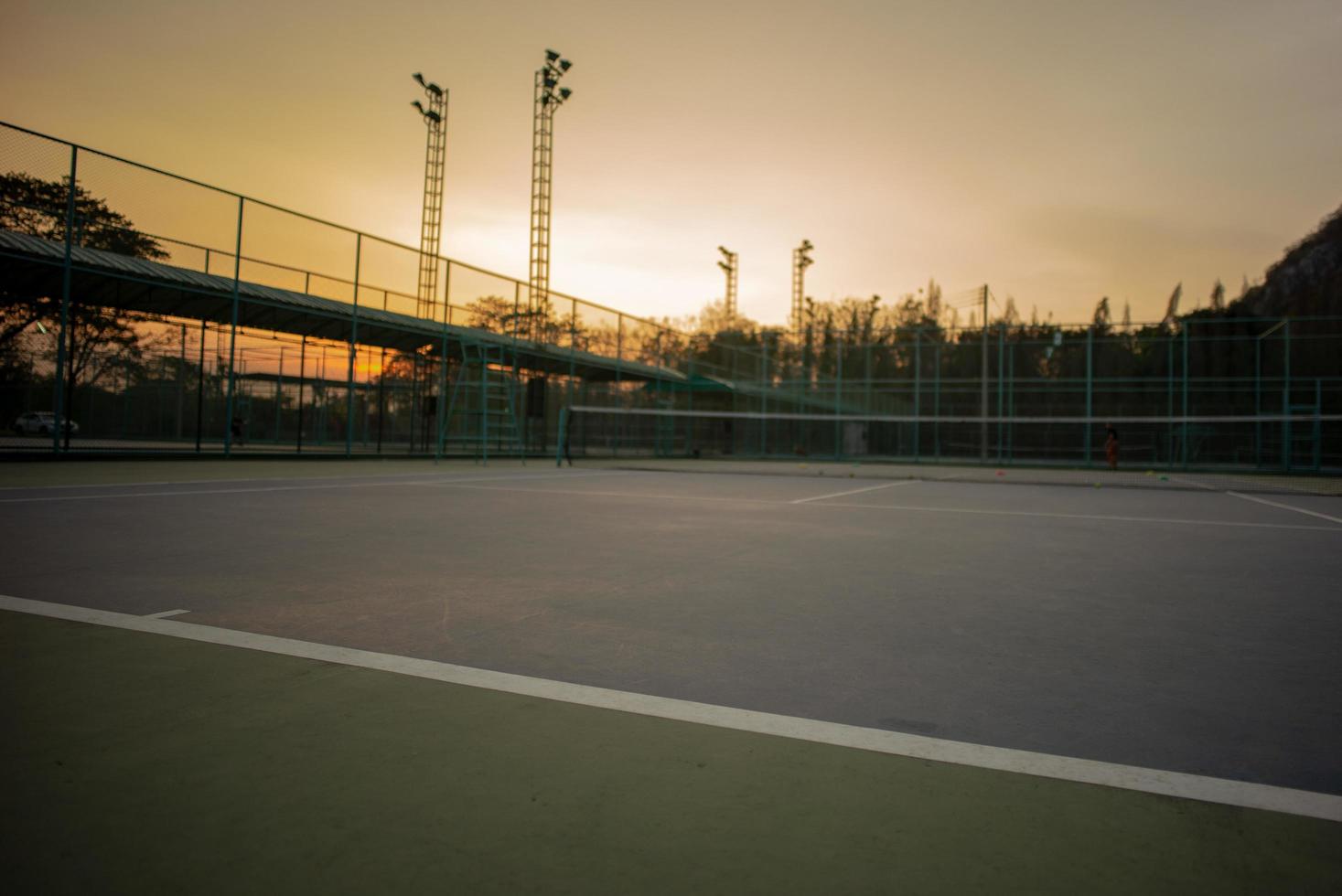 mise au point sélective de la ligne de base d'un court de tennis avec un fond de ciel coucher de soleil. paysage de lieu de sport. photo