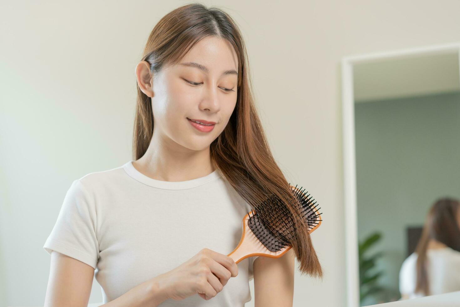 santé cheveux se soucier, beauté maquillage asiatique femme, fille en portant brosse à cheveux et brossage, ratissage sa longue tout droit cheveux à la recherche à réflexion dans miroir dans Matin routine après salon traitement, coiffure. photo