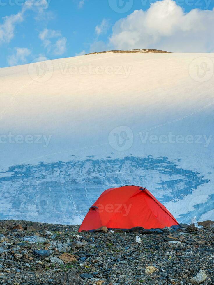 Matin vue une Orange renforcé tente contre le Contexte de une glacier sur une haute altitude plateau. photo