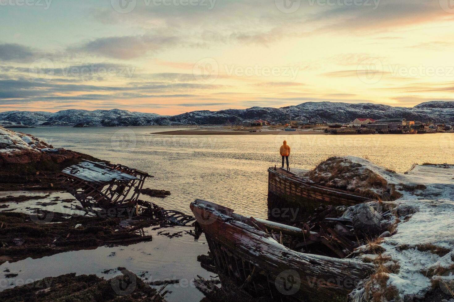 cimetière de navires, hiver le coucher du soleil vue dans un vieux pêche village sur le rive de le barents mer, le kola péninsule, teriberka photo