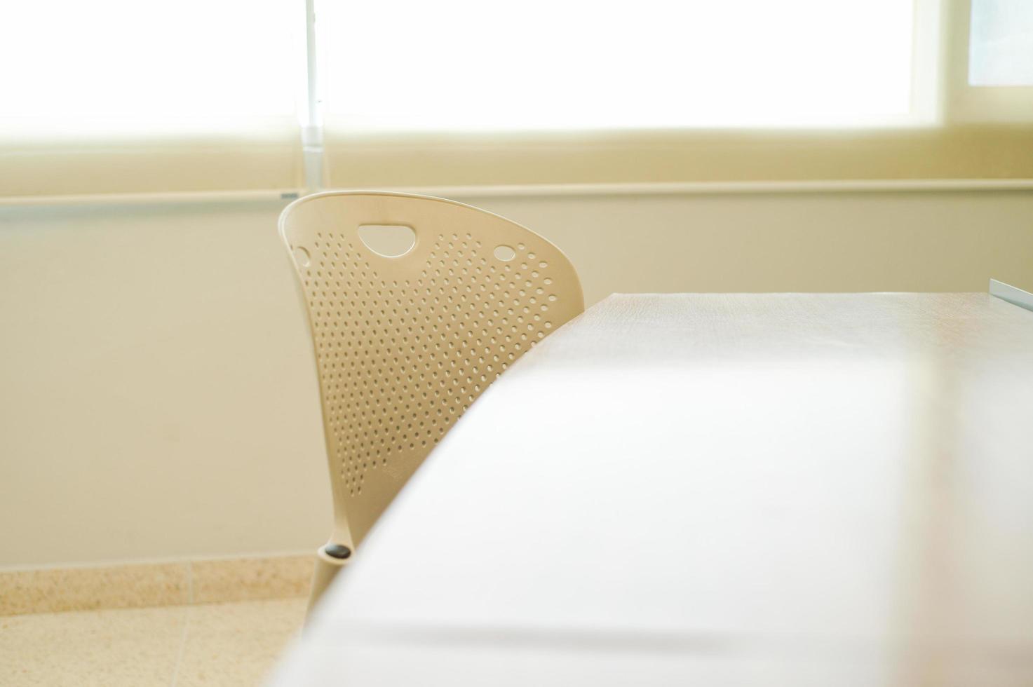 Mise au point sélective sur chaise et table en acier en salle de classe avec le soleil derrière l'arrière-plan du rideau défocalisé photo