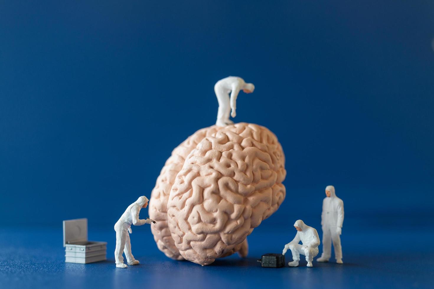 personnes miniatures, scientifiques observant et discutant du cerveau humain, des soins médicaux et du concept de service de médecin chirurgical. photo