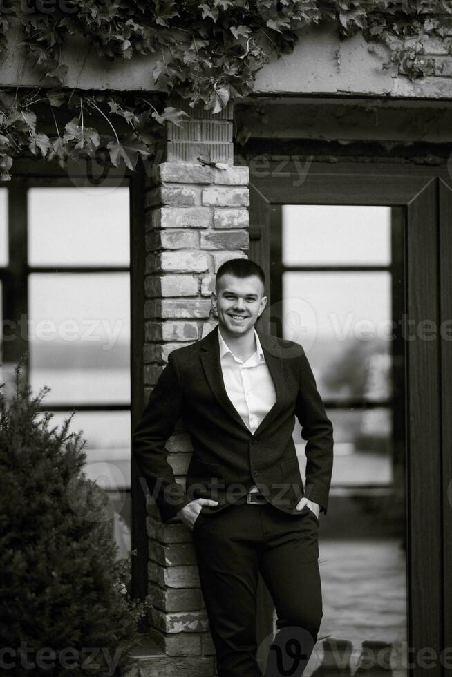 portrait de une Jeune gars jeune marié dans une foncé la laine costume photo