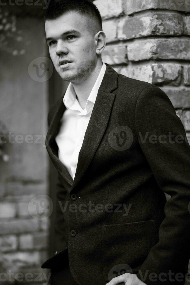 portrait de une Jeune gars jeune marié dans une foncé la laine costume photo