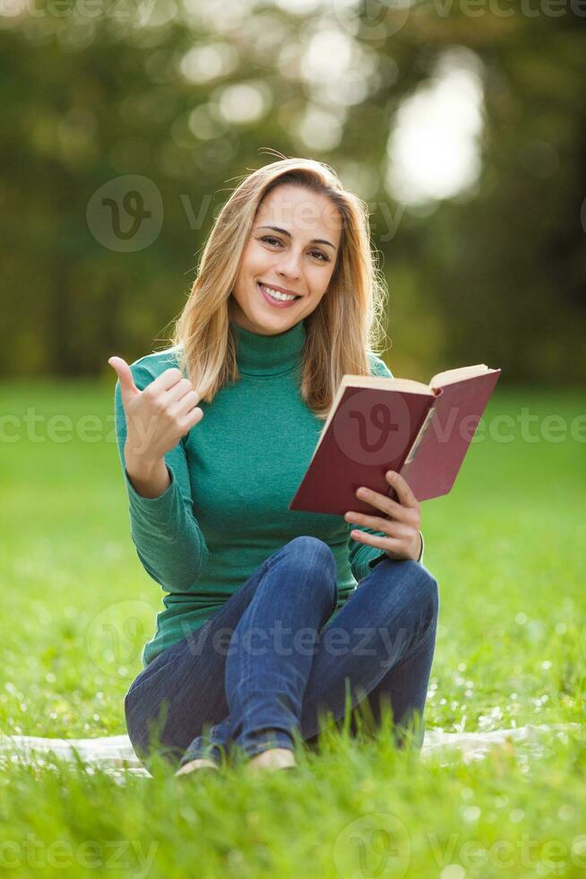 une femme dépenses temps en plein air et en train de lire une livre photo