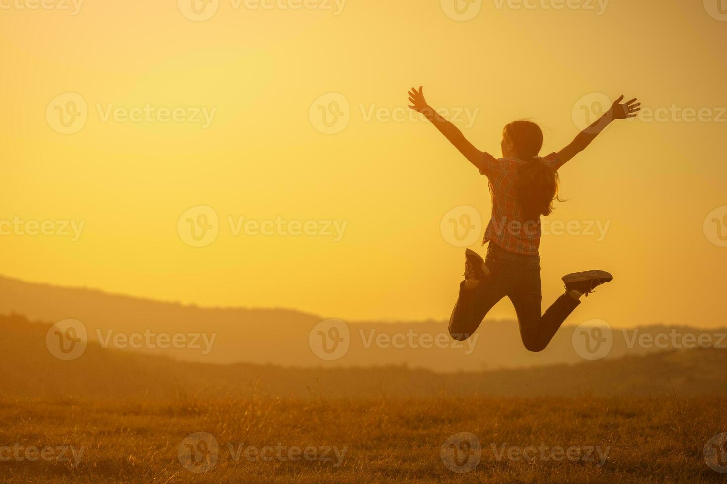 une fille sauter plus de le le coucher du soleil photo