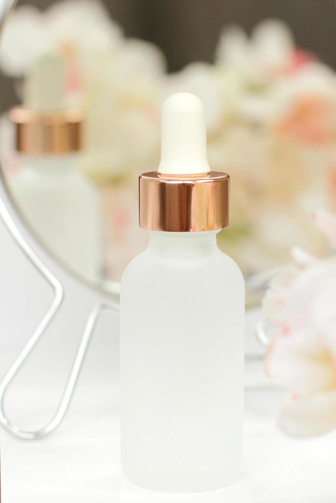 bouteille cosmétique avec miroir et fleurs photo