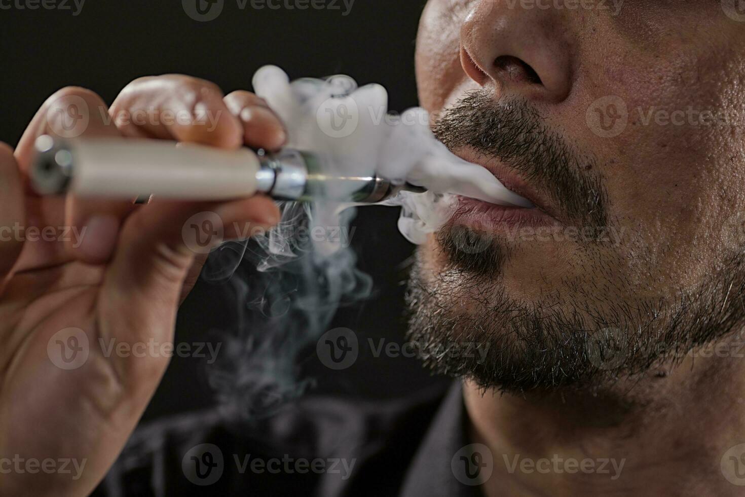 une homme fumeur un électronique cigarette photo