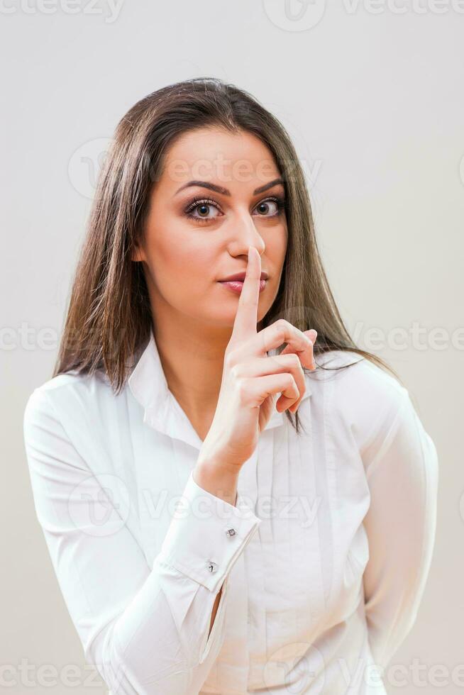 une femme dans une blanc chemise fabrication une silence geste photo