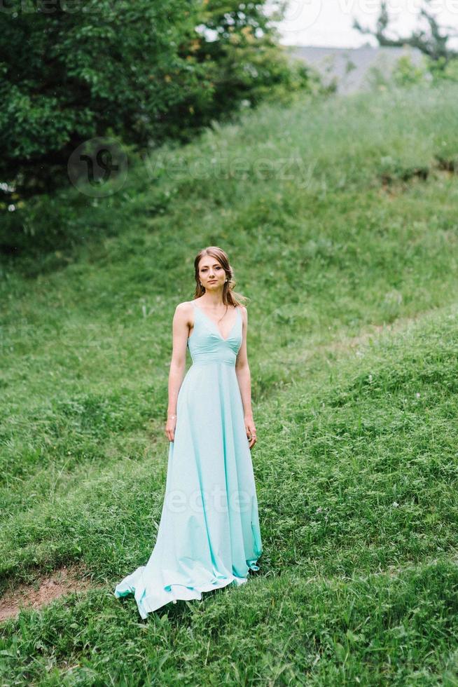 fille heureuse dans une robe longue turquoise dans un parc verdoyant photo