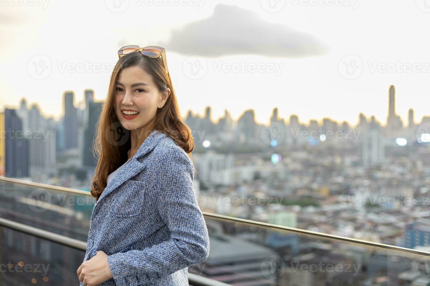 jeune femme d'affaires asiatique en costume formel avec tablette numérique debout à l'extérieur du gratte-ciel pour l'immobilier, le logement et le concept de développement urbain photo