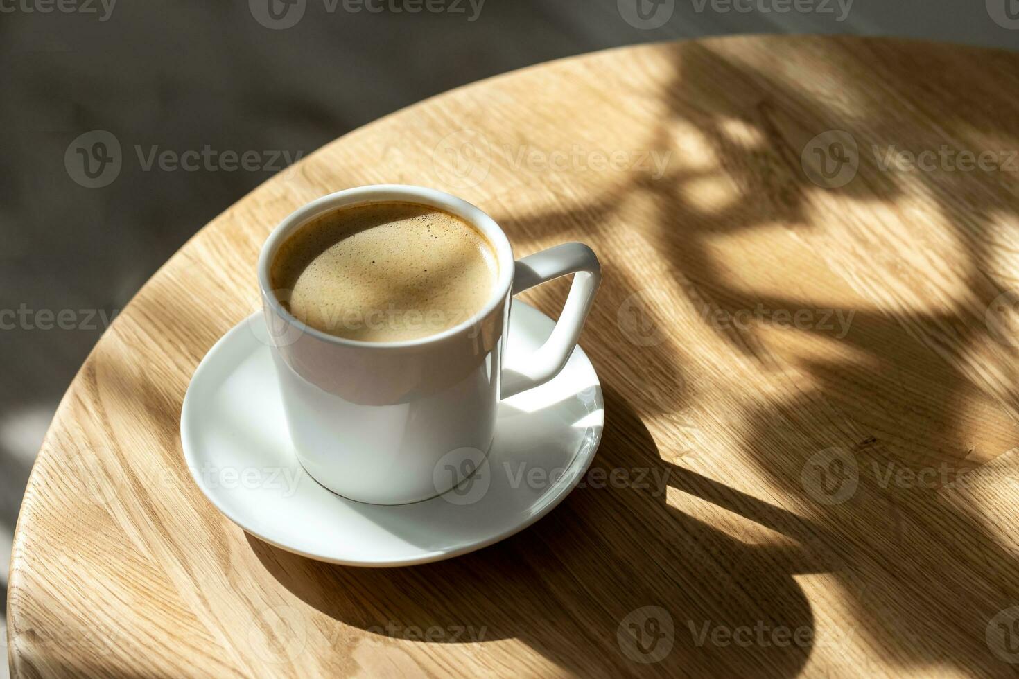 une blanc porcelaine tasse avec café sur une soucoupe des stands sur une rond table photo