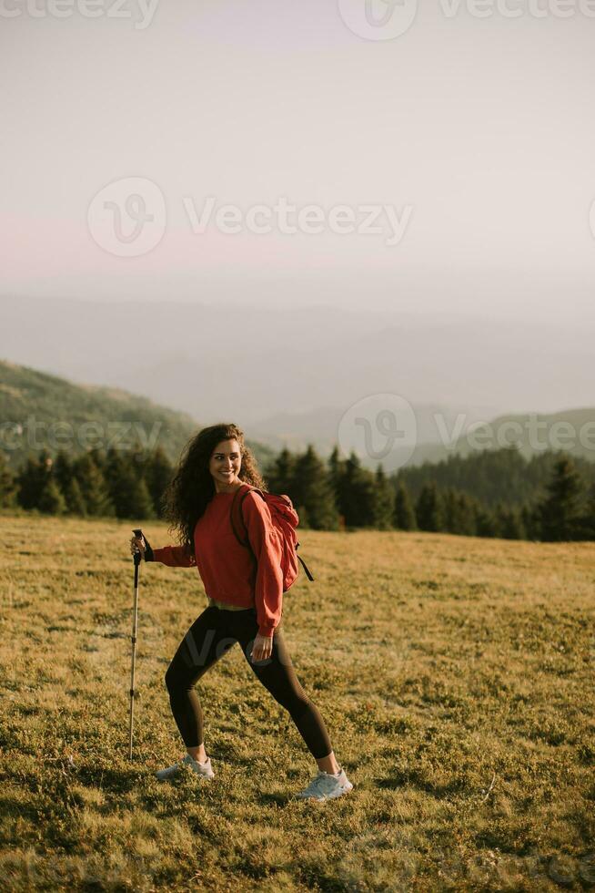 Jeune femme est prise une scénique une randonnée sur une colline, porter tout sa nécessaire équipement dans une sac à dos photo