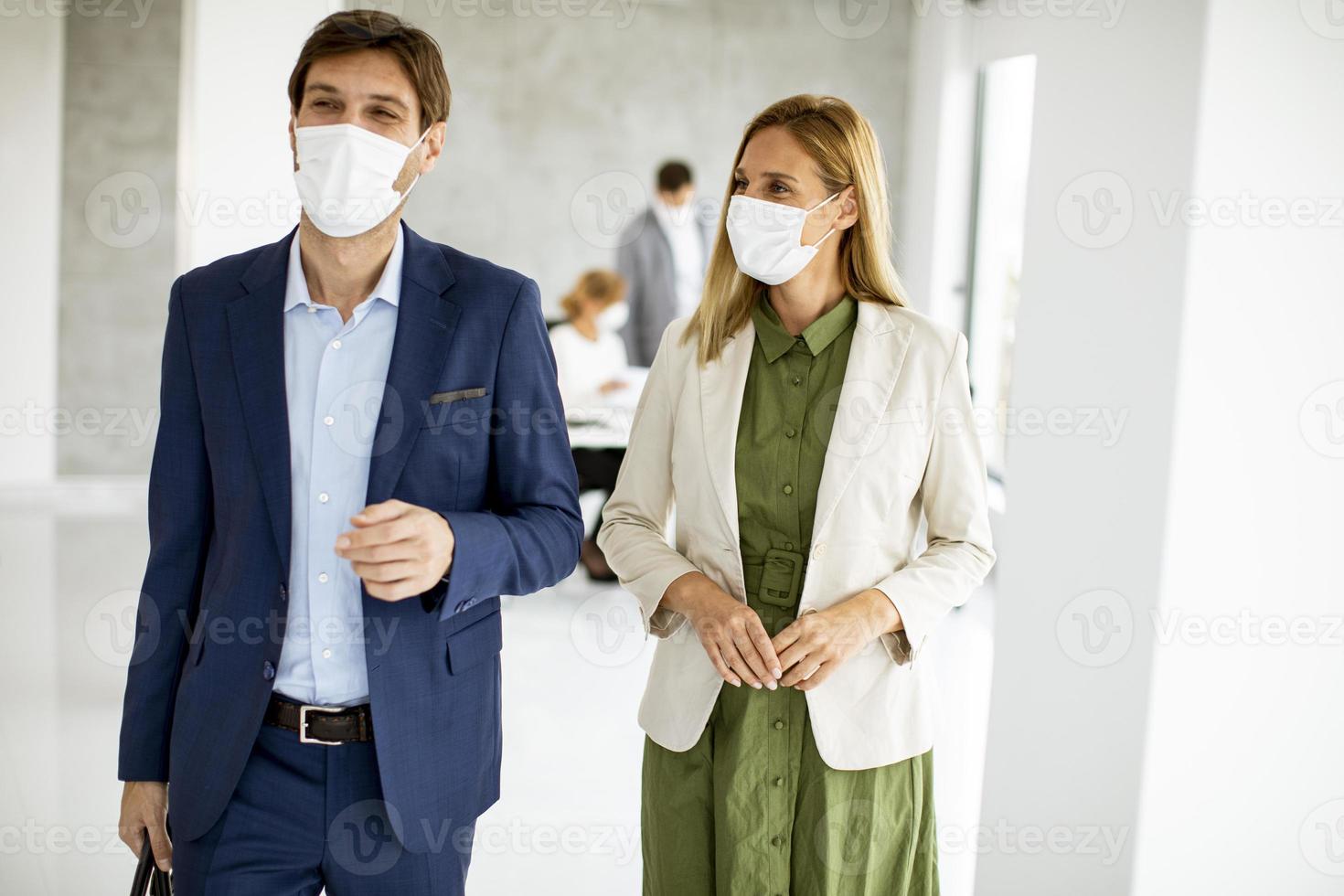 deux professionnels masqués marchant dans un bureau photo