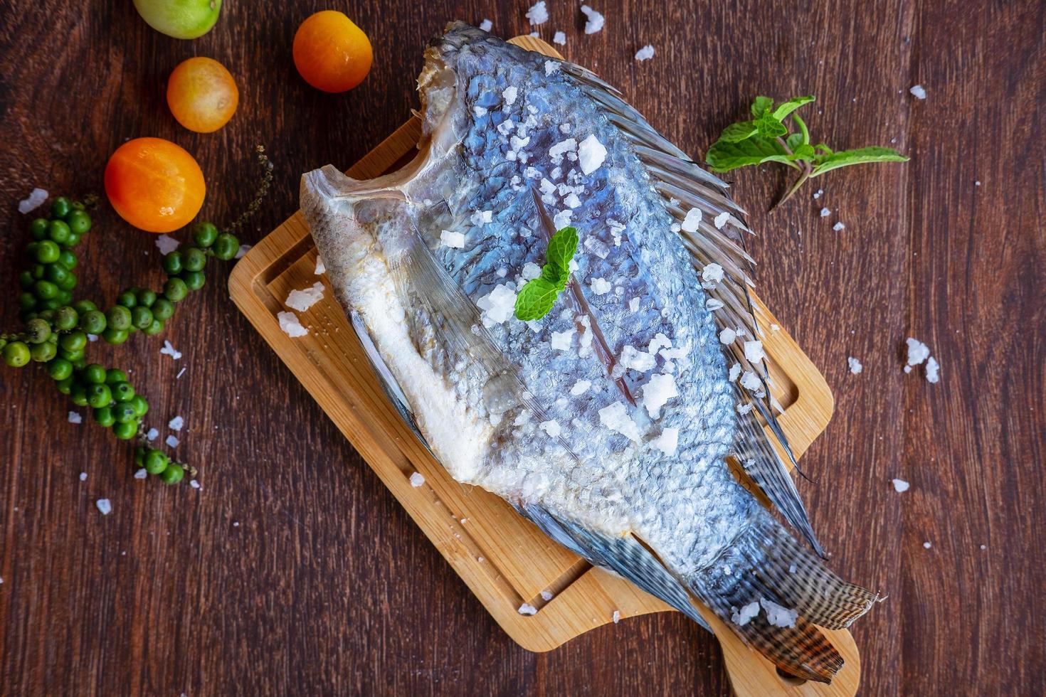 délicieux poisson frais sur fond sombre. poisson aux herbes aromatiques, régime alimentaire ou concept de cuisine. photo