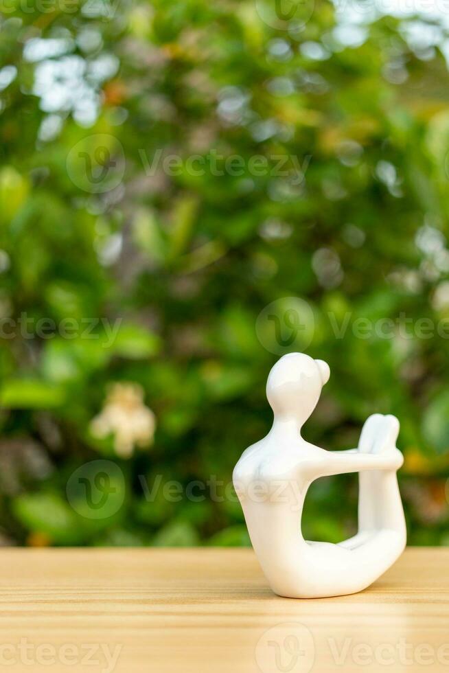 céramique yoga figurine de femme Faire yoga pose sur en bois sol et vert feuille Contexte photo