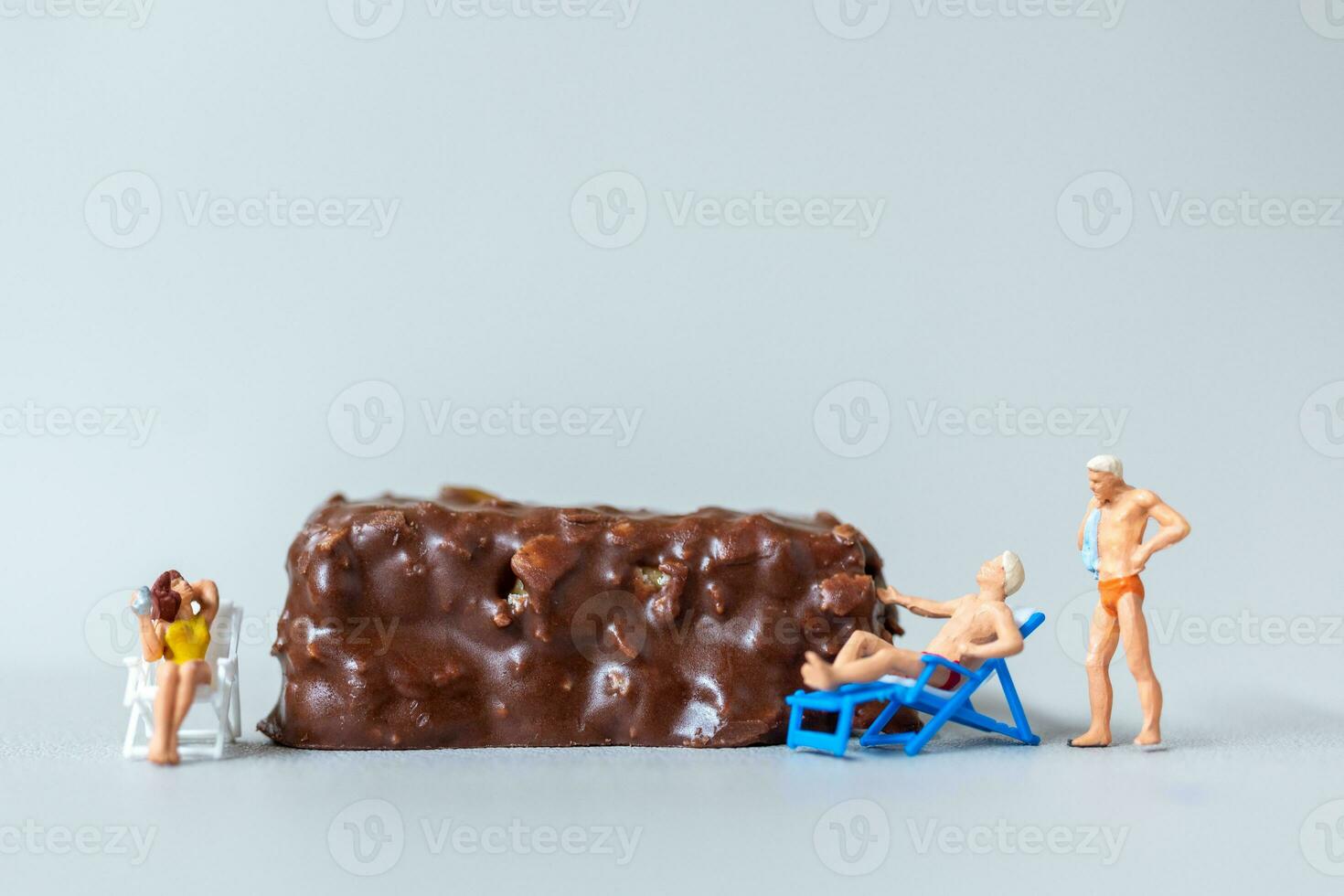 miniature gens portant maillot de bain relaxant sur Chocolat bars sur gris Contexte. monde Chocolat journée concept photo