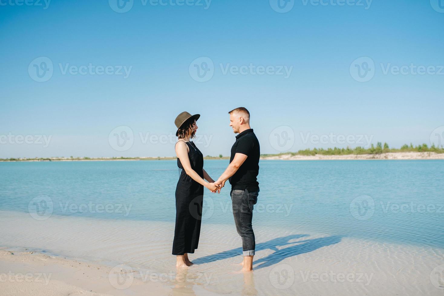 jeune couple un mec avec une fille en vêtements noirs marchent sur le sable blanc photo