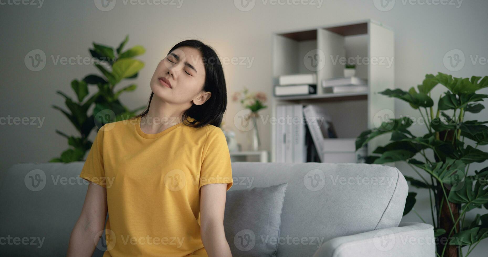 Jeune asiatique femme épaule douleur dans le vivant pièce à maison. photo