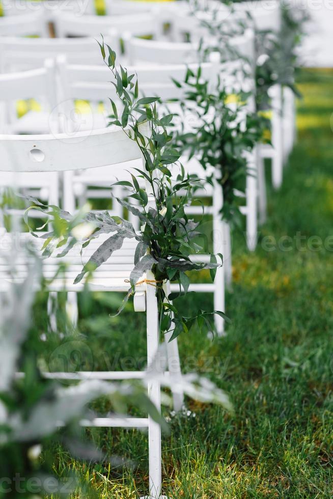 chaises blanches décorées lors d'une cérémonie de mariage photo