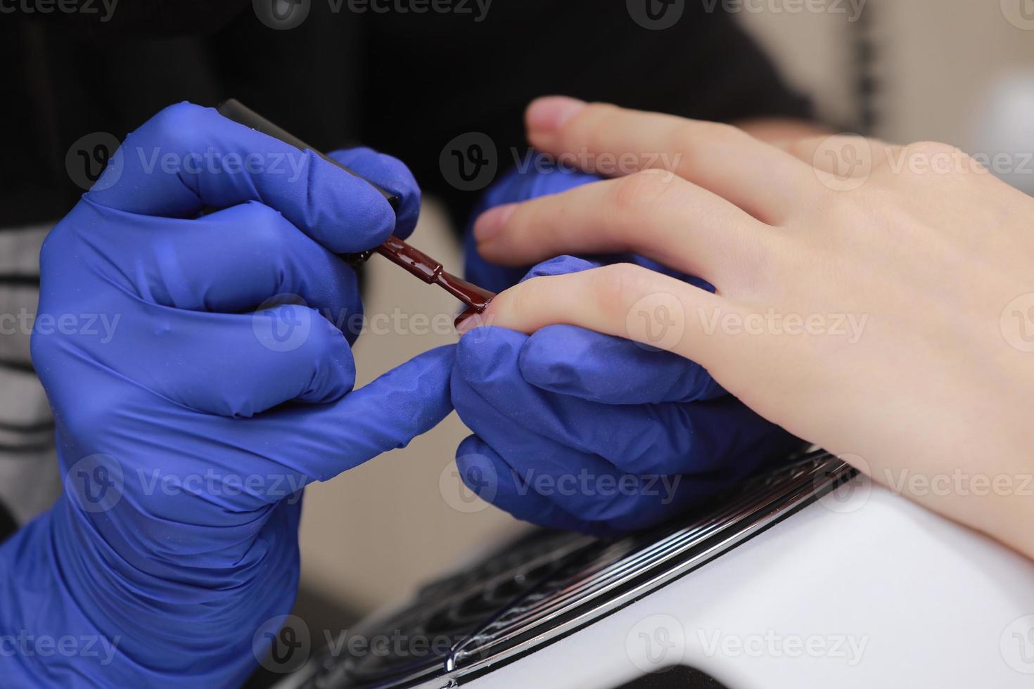 Maître manucure en gants de protection lors d'une manucure au salon de beauté photo